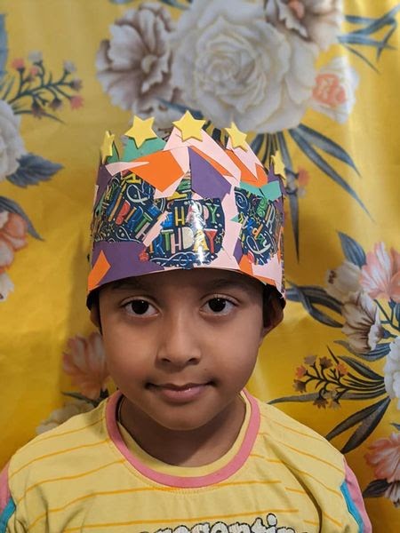 A close-up photo of a boy wearing a crown with star design
