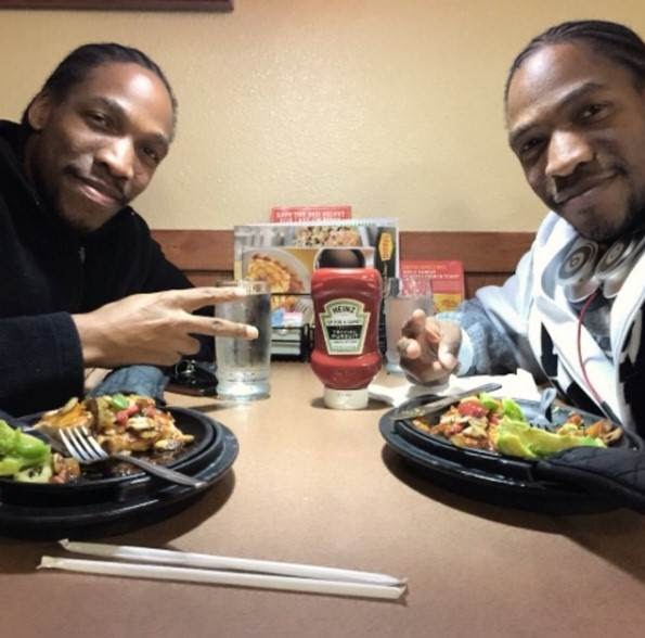 Arthell and Darnell showing a peace sign while eating at a restaurant.