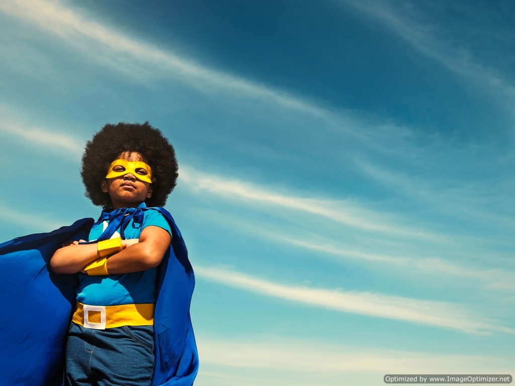 A young and proud girl of color wearing a superhero costume.