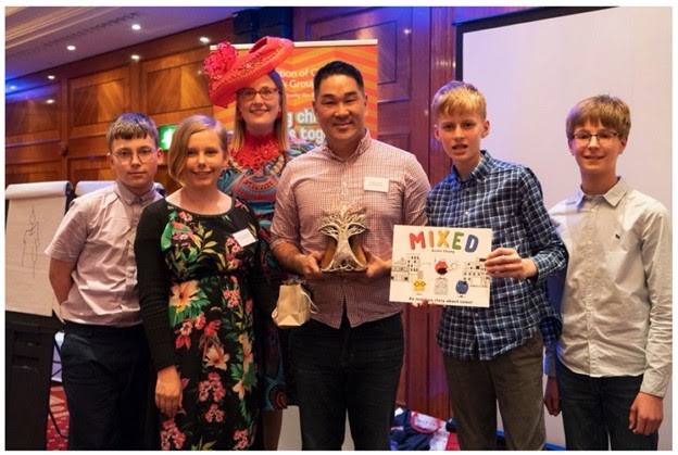Picture of Arree Chung with boys and girls around him as he received the Federation of Children's Book Groups (FCBG) Award in 2019
