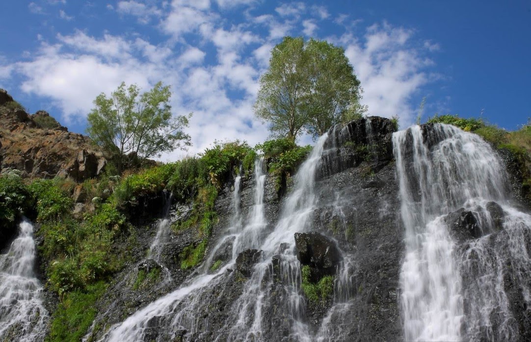 Waterfall scenery with trees and cloudy sky